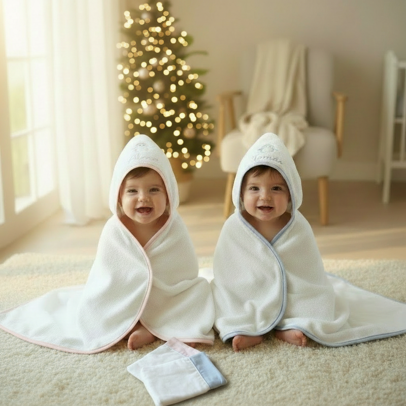 Happy babies in hooded towels with calm festive tree background